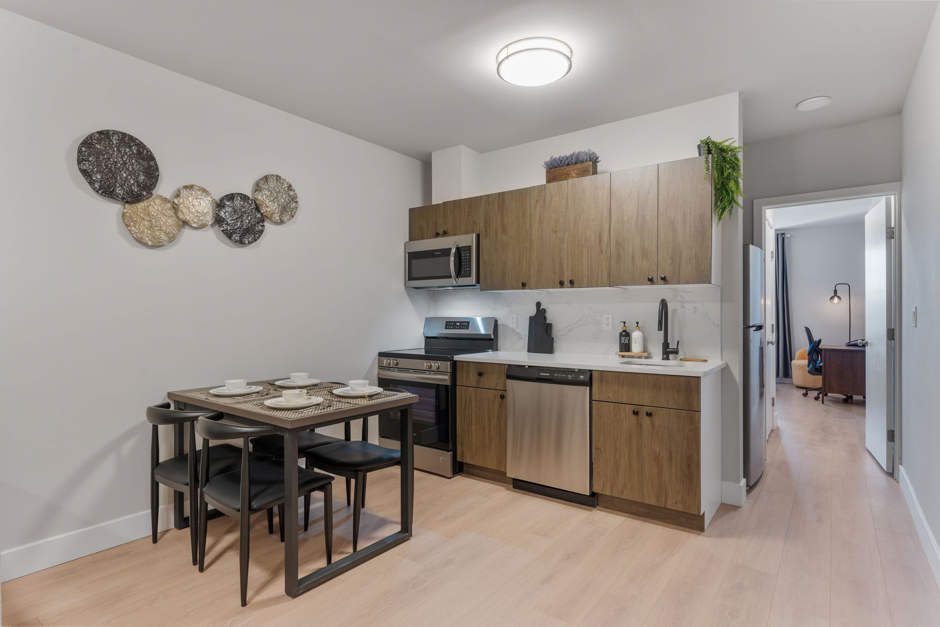A kitchen with wooden cabinets and stainless steel appliances and a dining table and chairs.