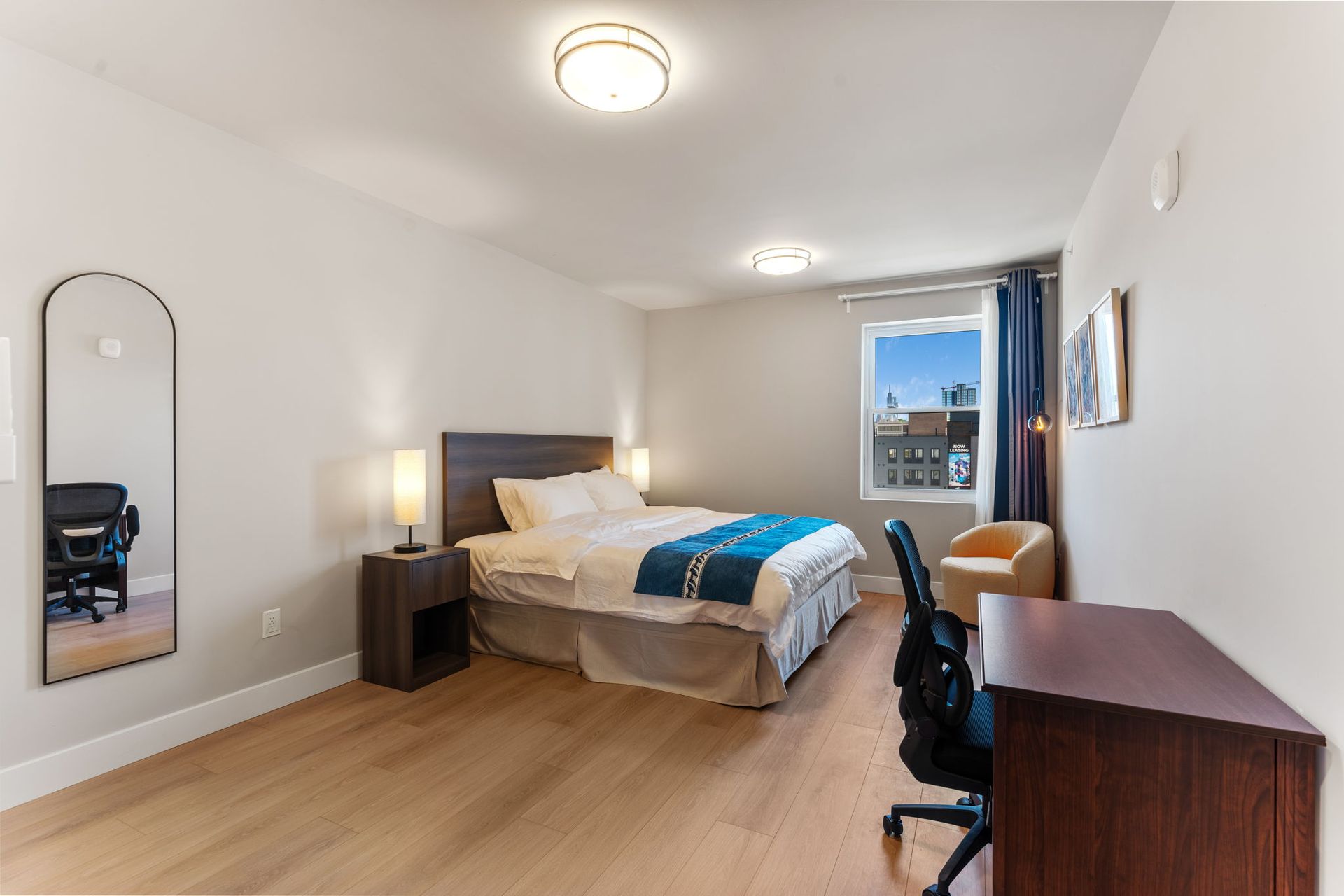 A yellow chair is sitting in front of a window in a bedroom.