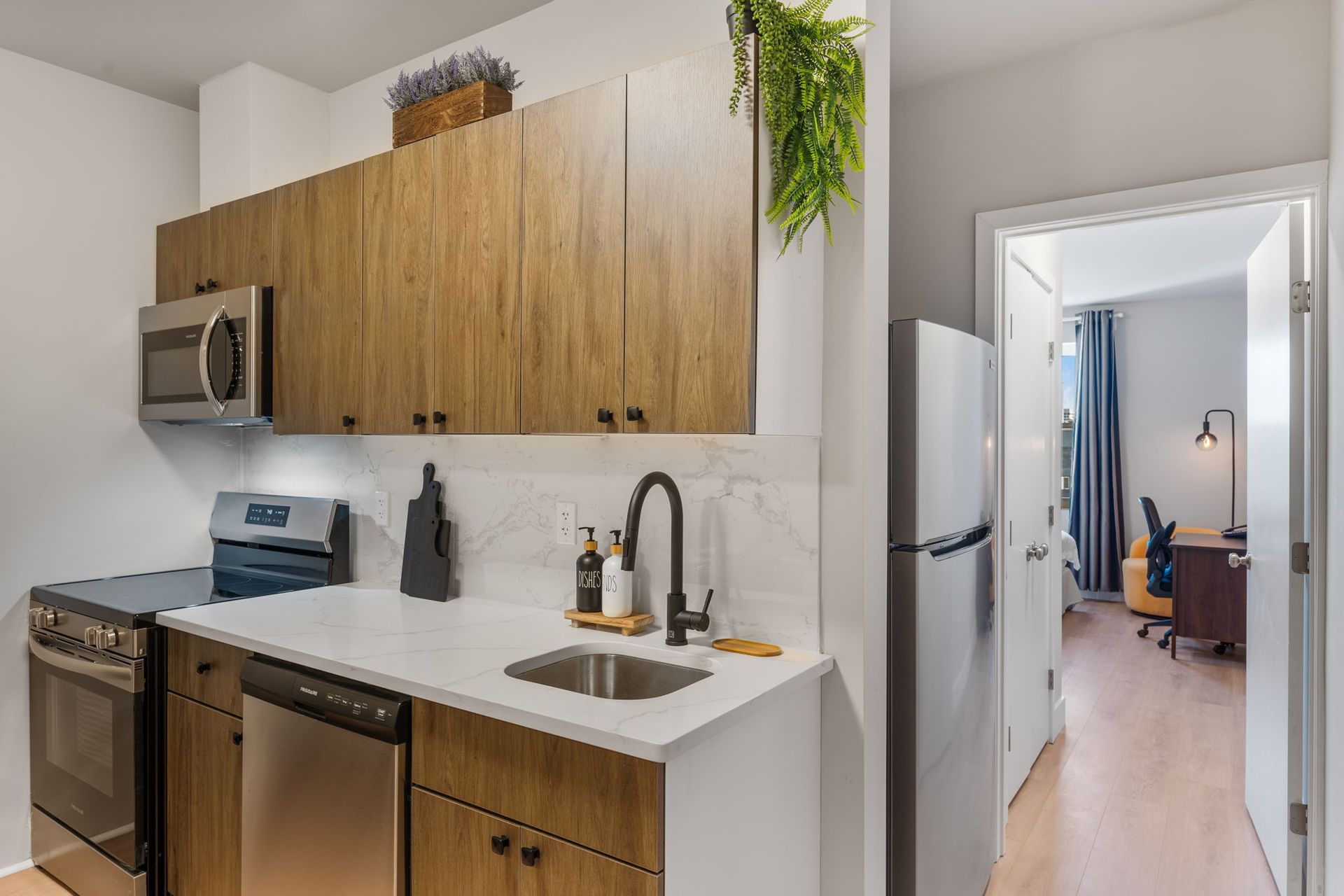 A kitchen with wooden cabinets , stainless steel appliances , a sink and a refrigerator.