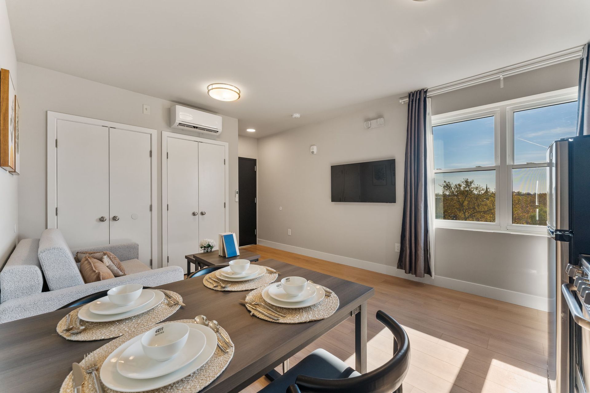 A living room with a dining table and chairs and a flat screen tv.