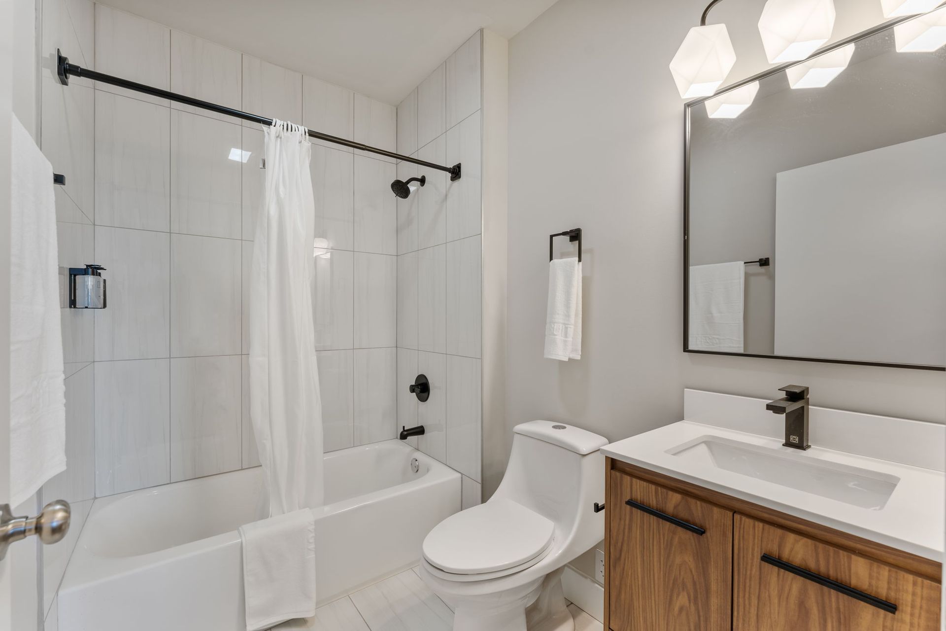 A bathroom with a toilet , sink , bathtub and mirror.