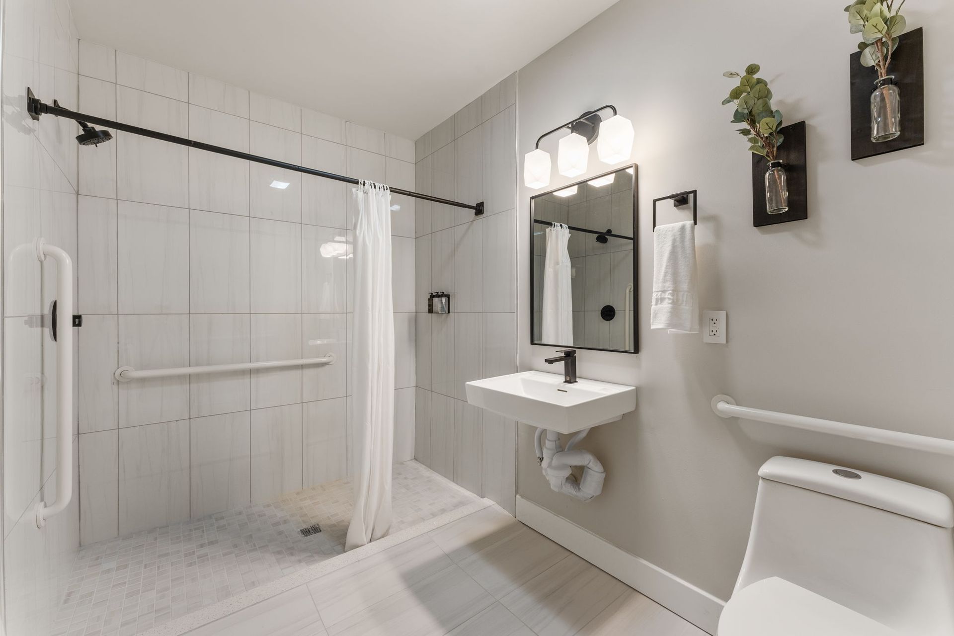 A bathroom with a sink , toilet , shower and mirror.