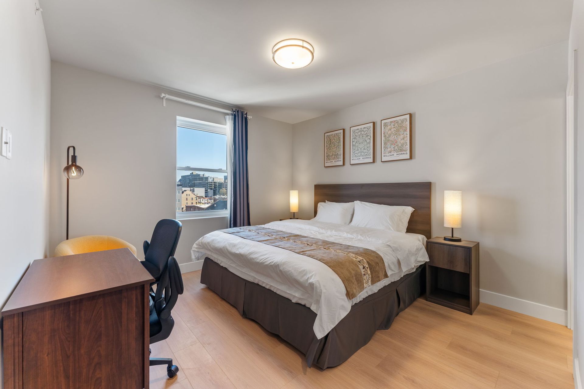 A bedroom with a king size bed , nightstand , desk and chair.