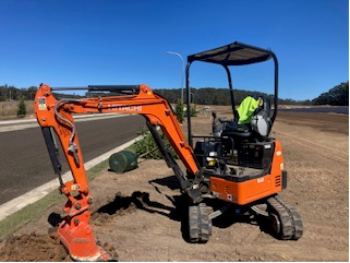 Mini Excavator on Sand In Front of Water — Michael Flick Horticulture in Coffs Harbour, NSW