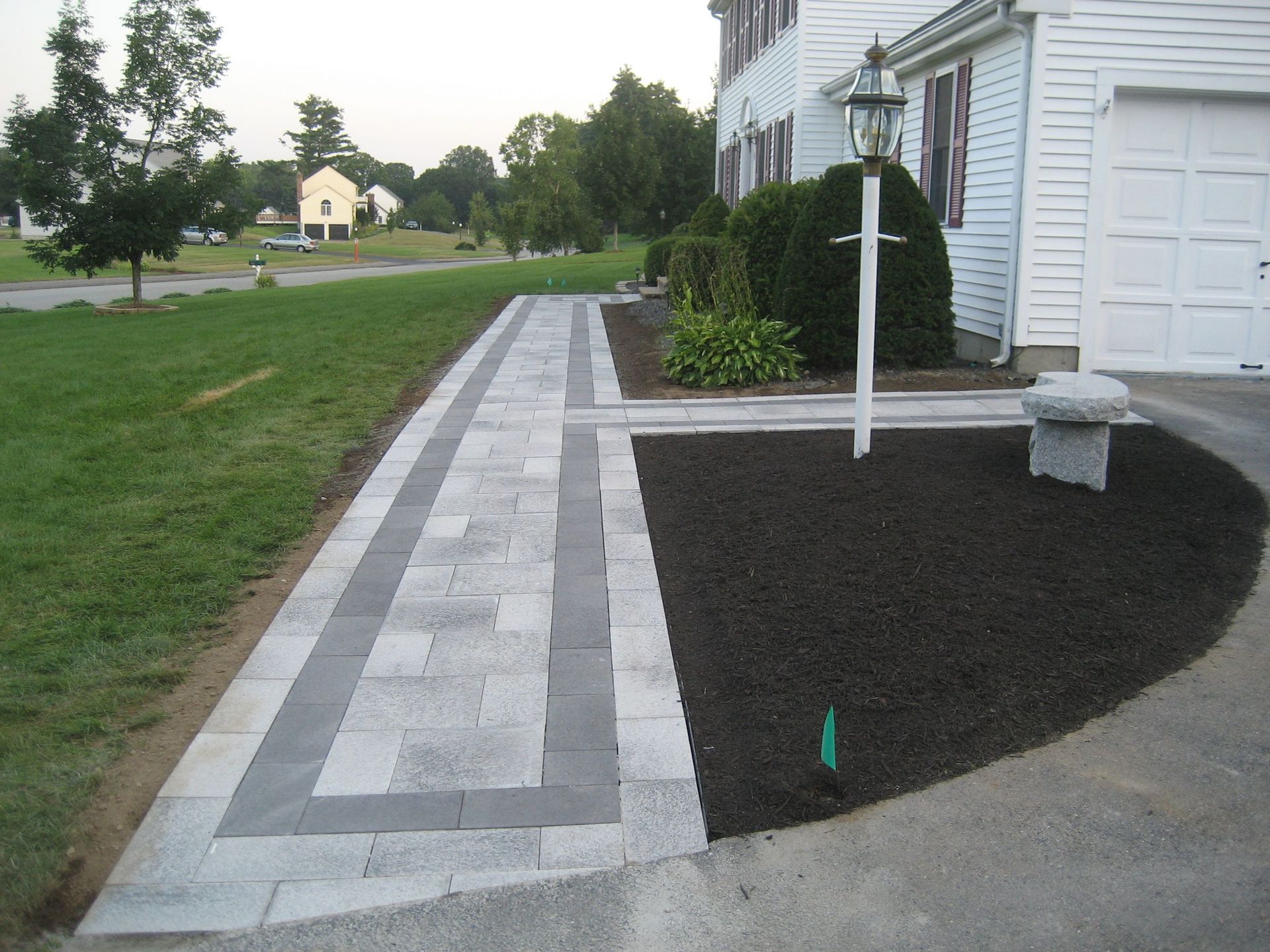 A walkway leading to a patio with a deck and umbrella.