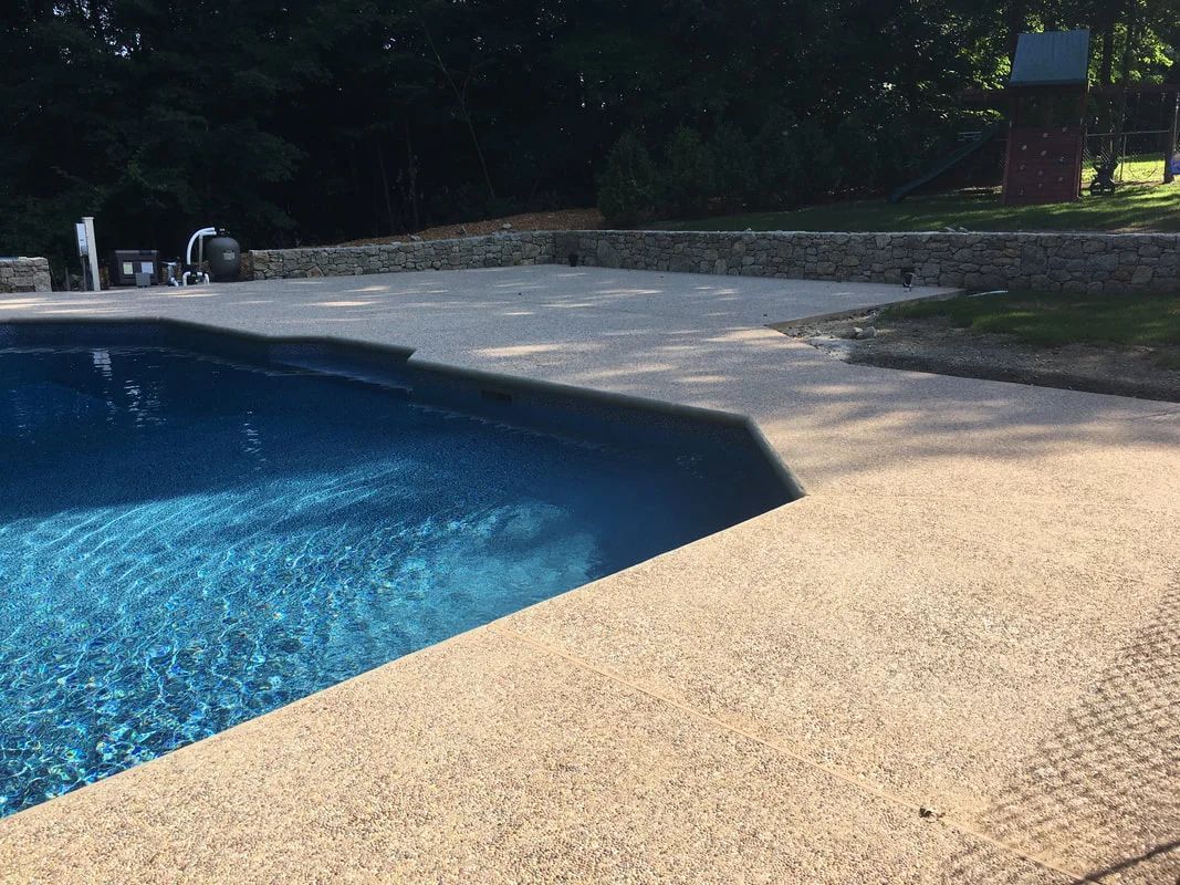 A large swimming pool is surrounded by a concrete patio.