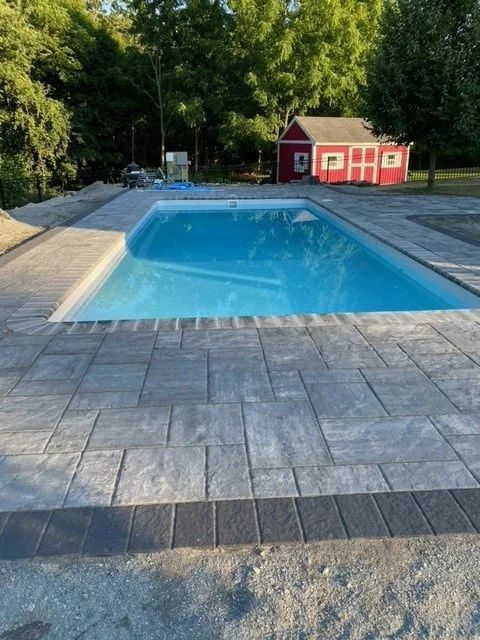 A large swimming pool with a red barn in the background