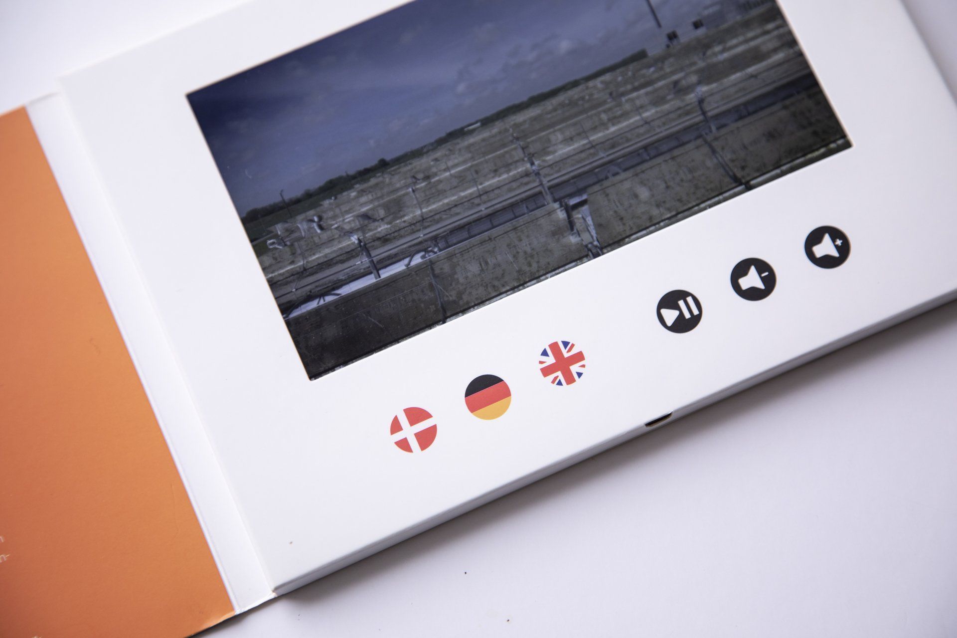 Åben bog med et landskabsfoto og små flagikoner på en hvid side