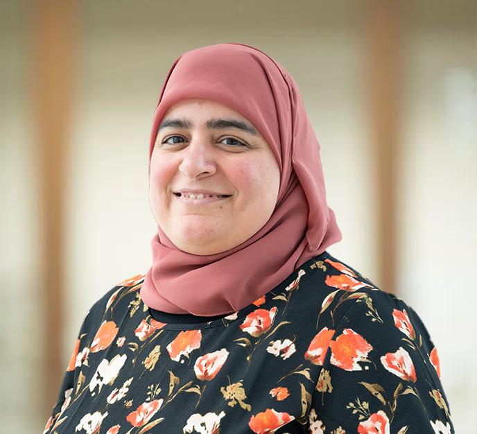 En kvinde iført blå hijab smiler til kameraet.