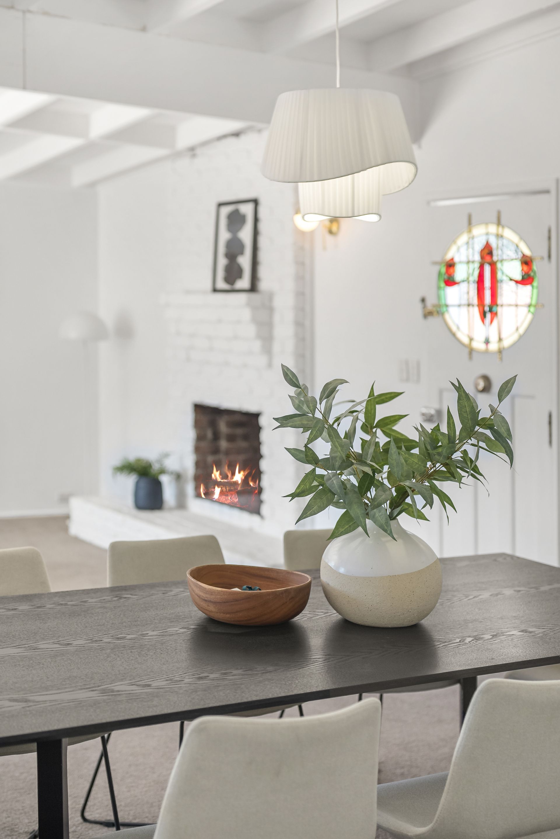 Estate to Sale Projects - Bright white dining room with table, chairs, plant, fireplace, and stained-glass window