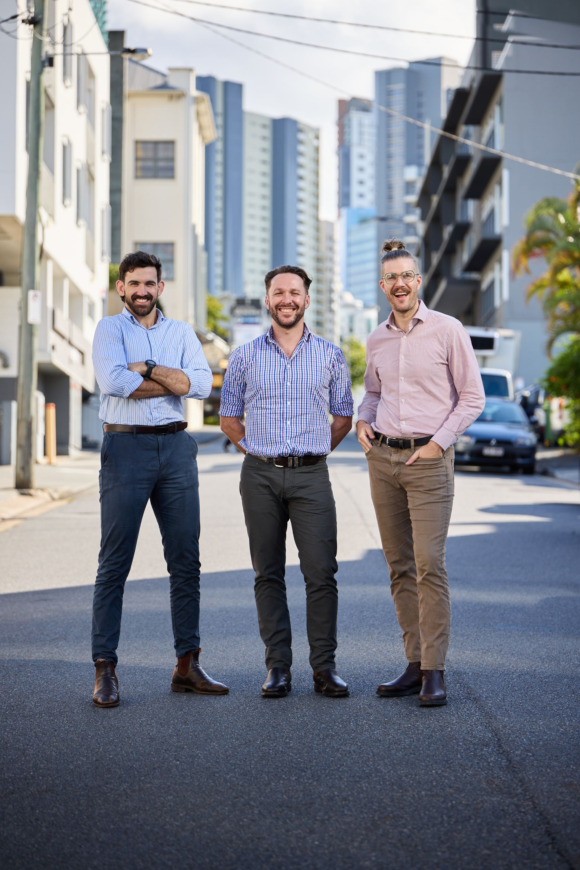 Link Advance - Three men standing on a city street with tall buildings in the background, smiling at the camera.