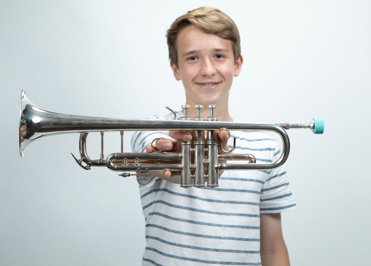 Buzz Buddy - Young person holding a silver trumpet horizontally against a light background