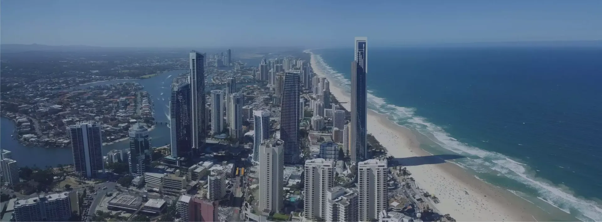 Silver Asset Services - Aerial view of a coastal city skyline beside a sandy beach and blue ocean.