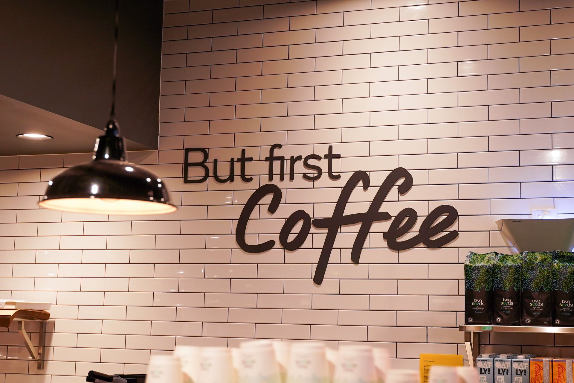 A brick wall with the words but first coffee written on it