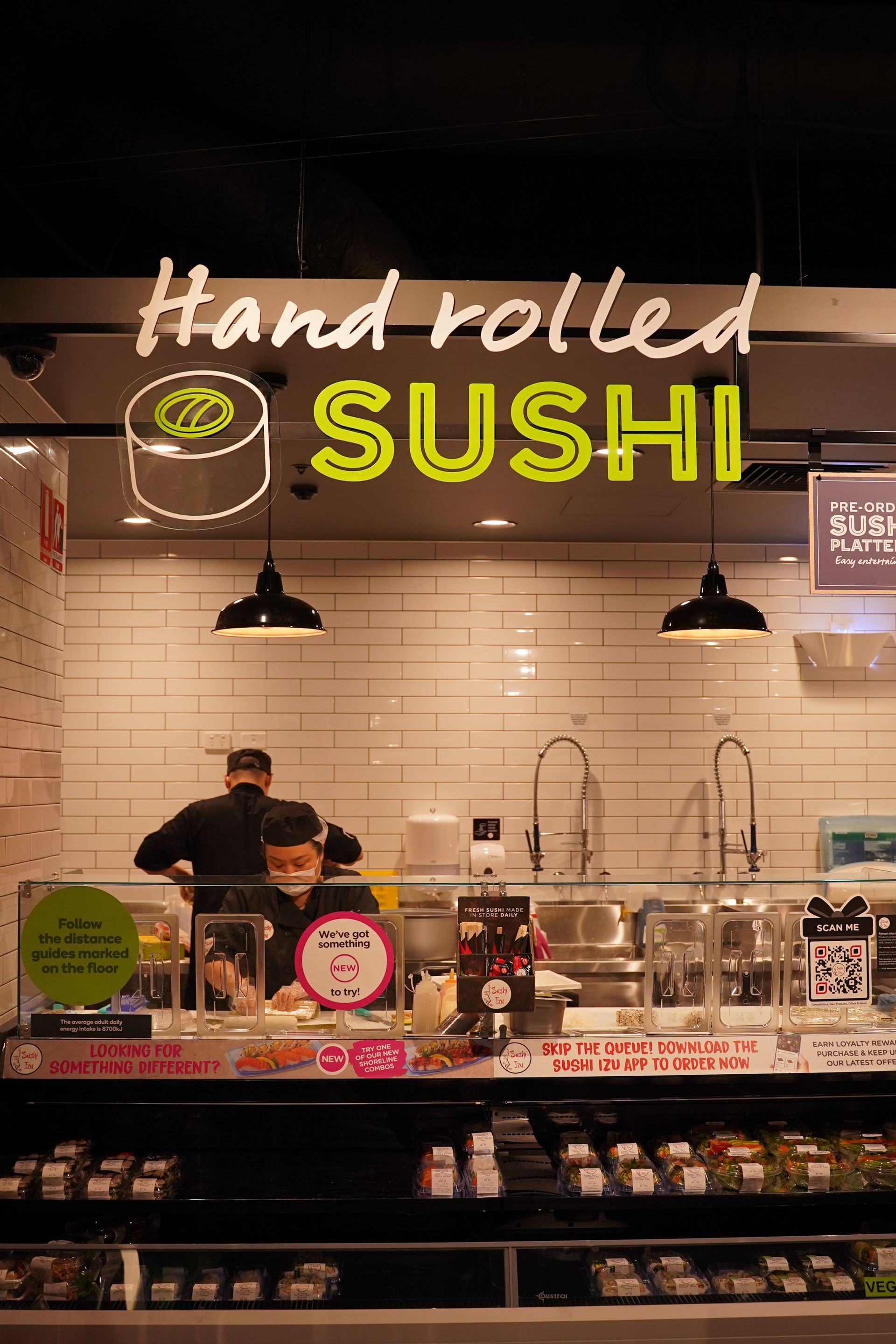 A sushi restaurant with a neon sign that says hand rolled sushi.