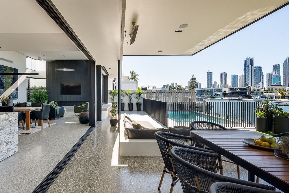 DMG Build - Modern balcony with dining table, woven chairs, pool, and city skyline view