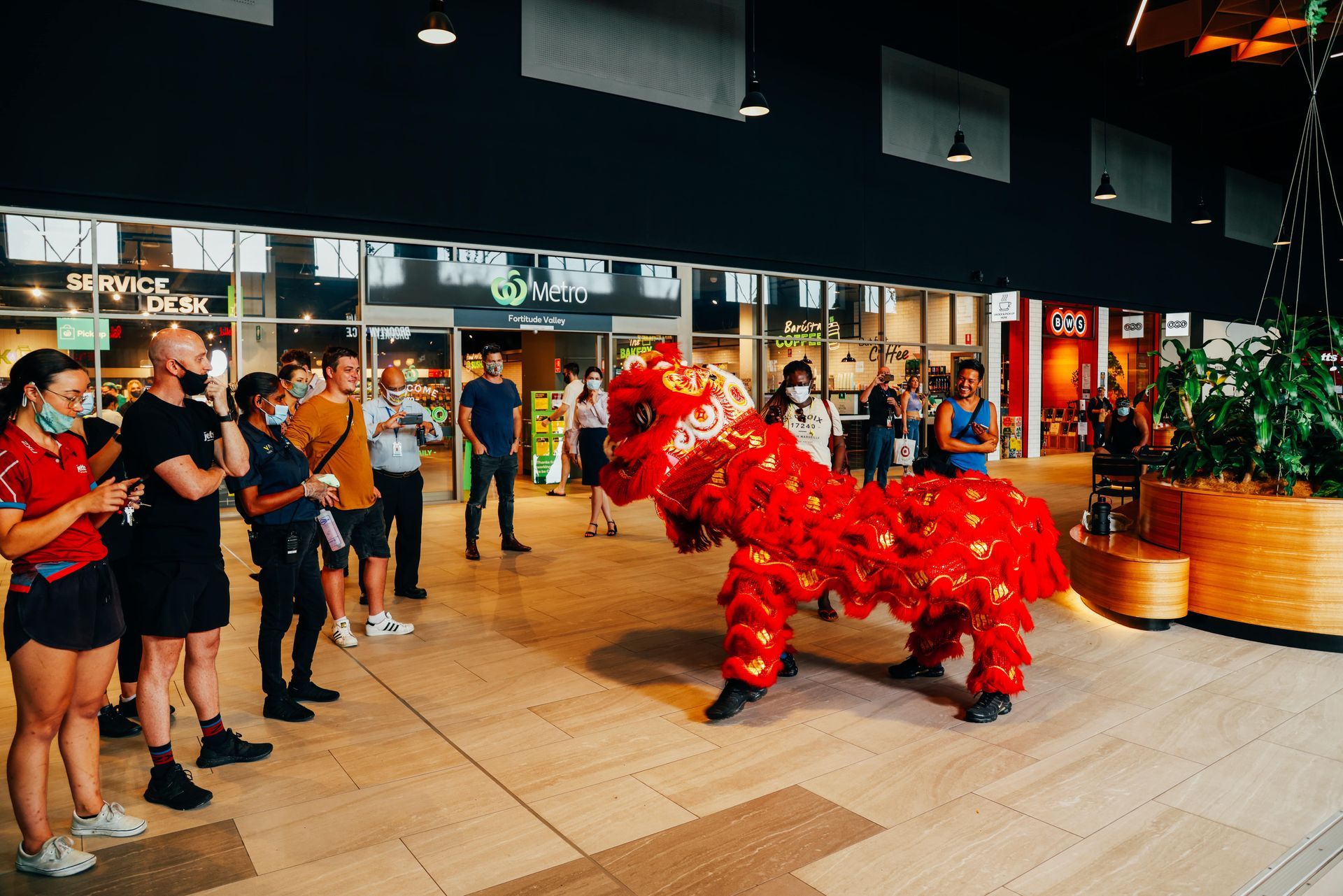 A group of people are watching a lion dance in a mall.