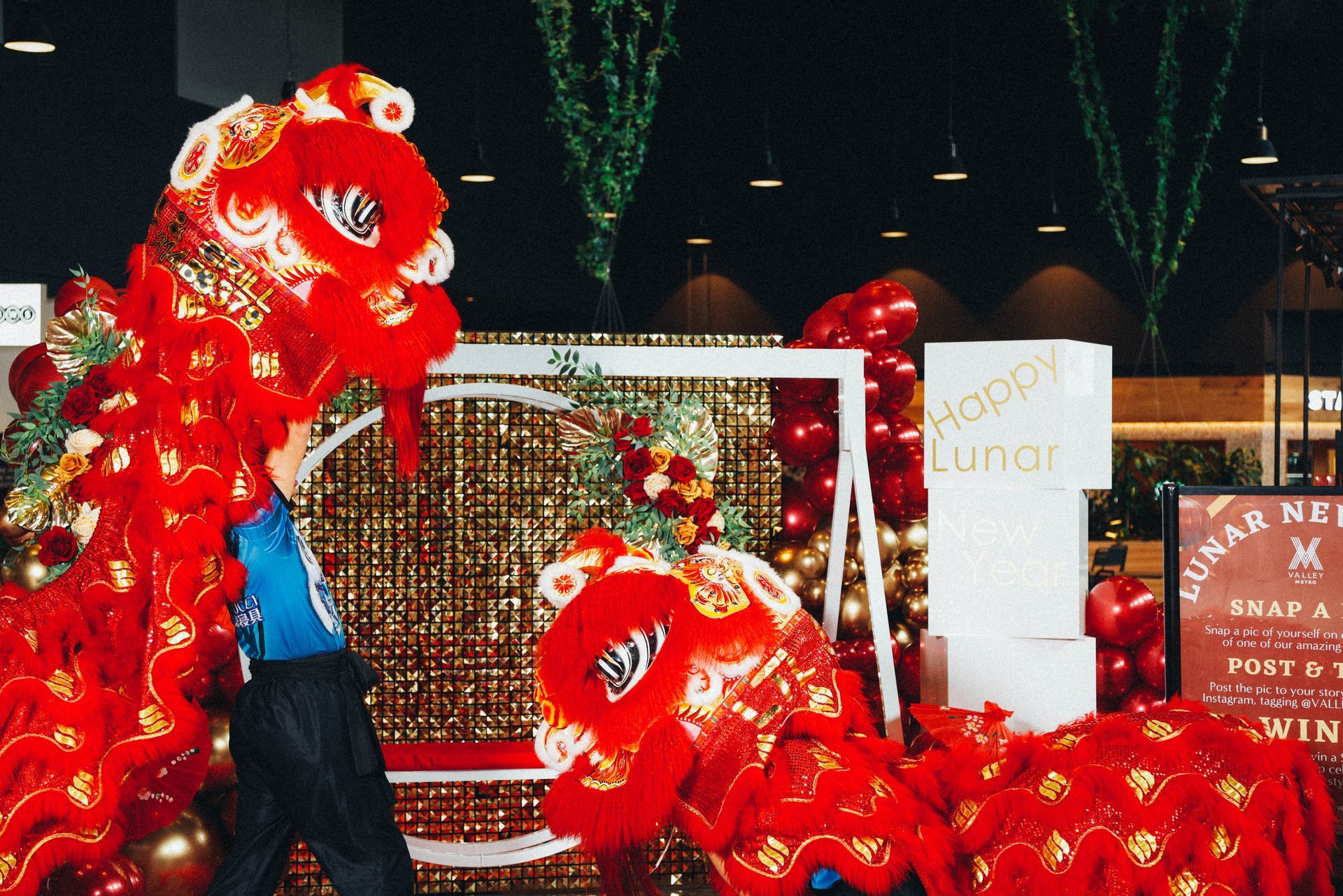 A man is holding a red lion head in front of a sign that says happy lunch