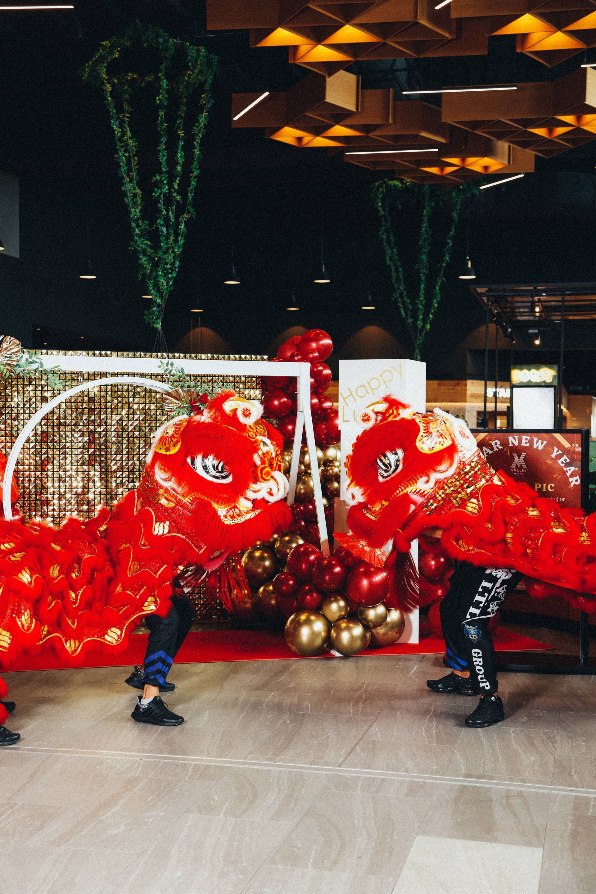 Two people are performing a lion dance in a room