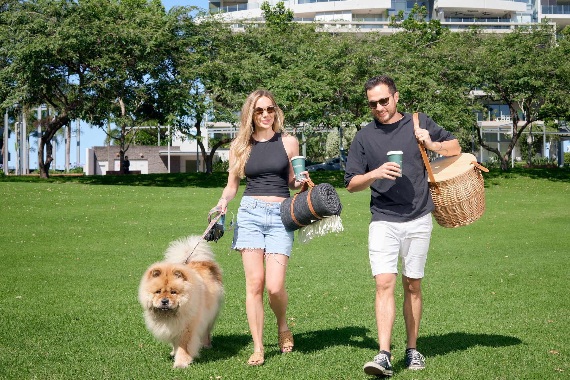 A man and a woman are walking a dog in a park.