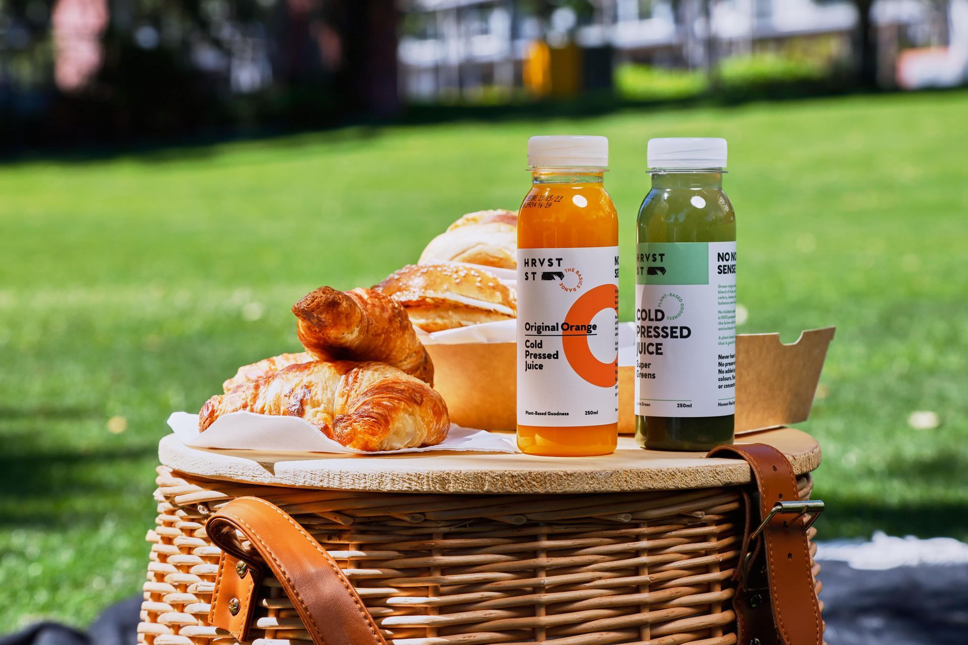 A picnic basket filled with food and two bottles of juice.