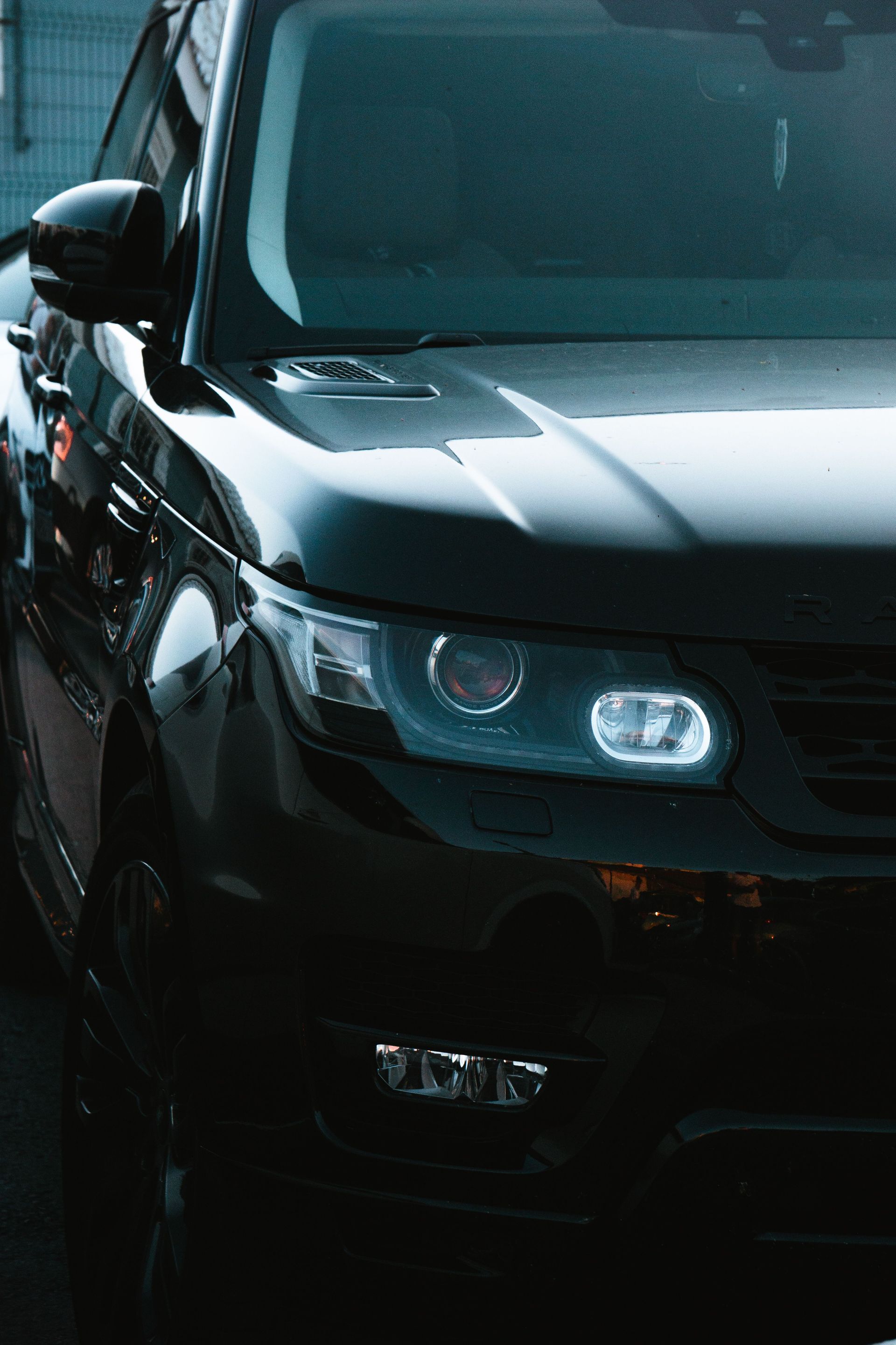 Connexion - Front view of a black SUV with headlights on in a wet, rainy street.
