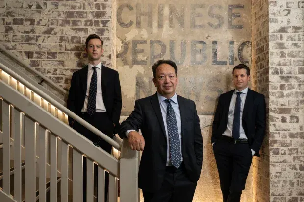 Geometrica Fund - Three men in suits standing on a staircase in front of a wall reading “Chinese Republic”