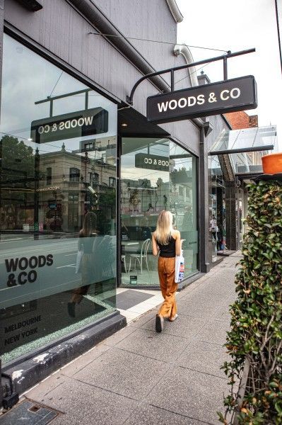 Woods & Co - Person walking past Woods & Co storefront on a city sidewalk