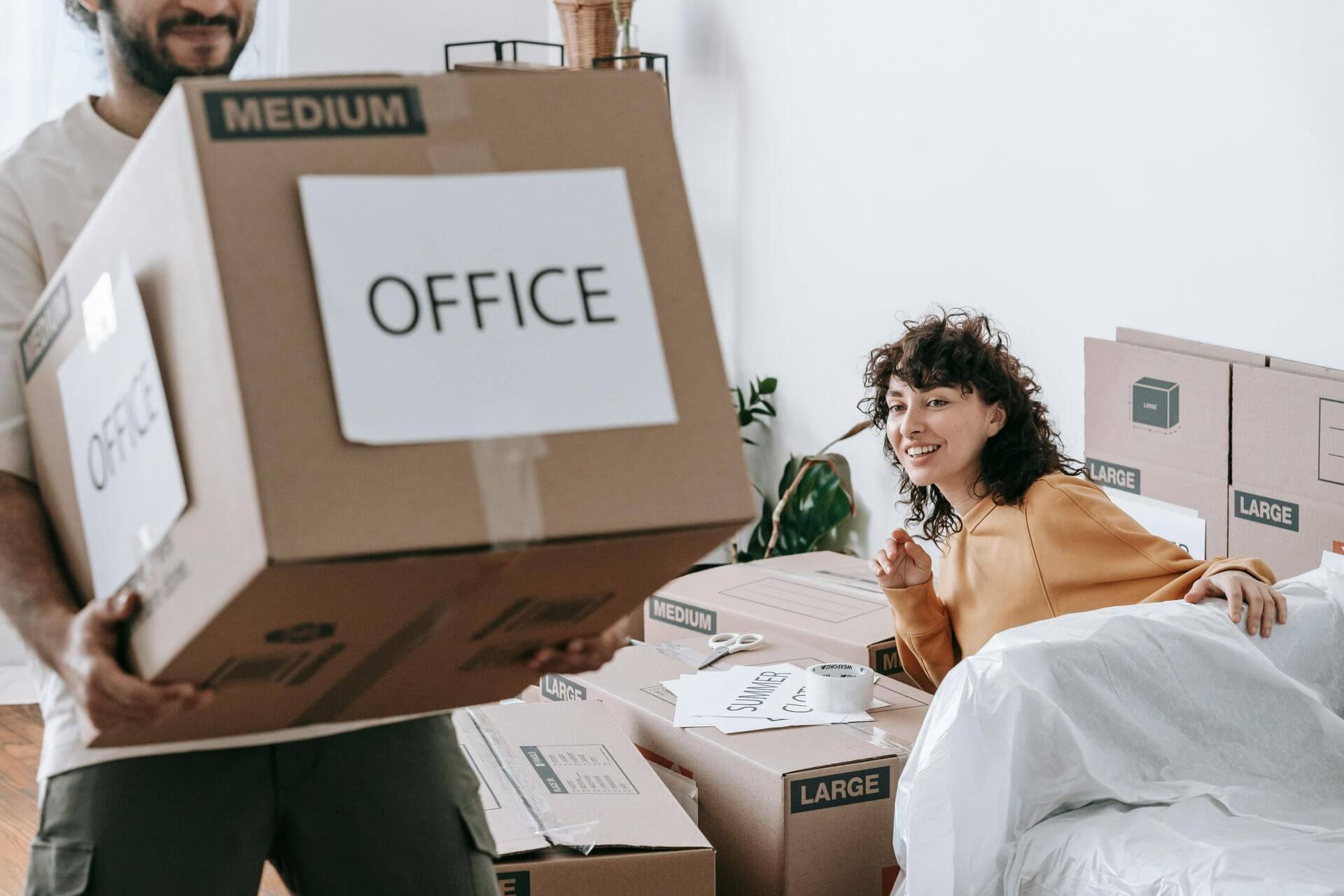 woman guiding man to where he should lay the box he has on his hands