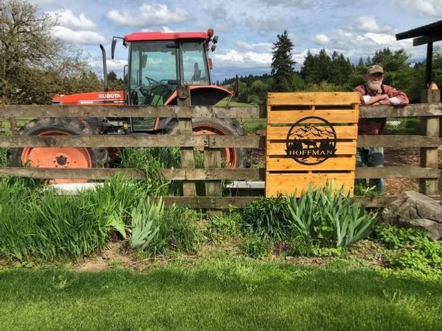 Red tractor behind a wooden fence beside a yellow farm sign in a grassy field