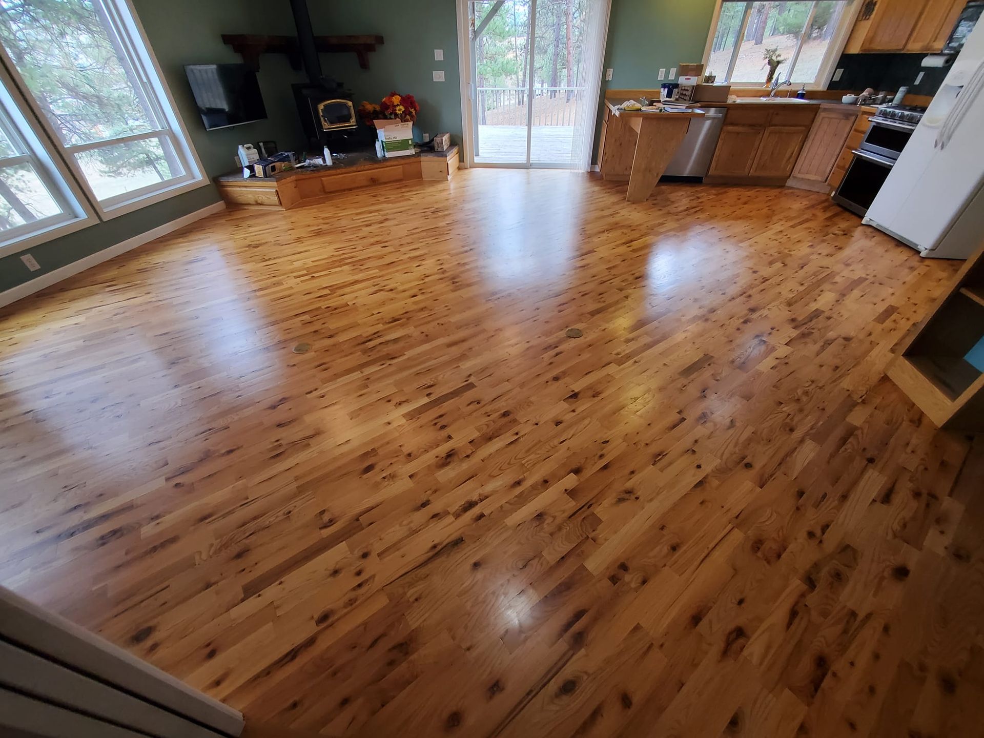 Wood-floored interior with a fireplace and large windows. The kitchen is visible on the right.