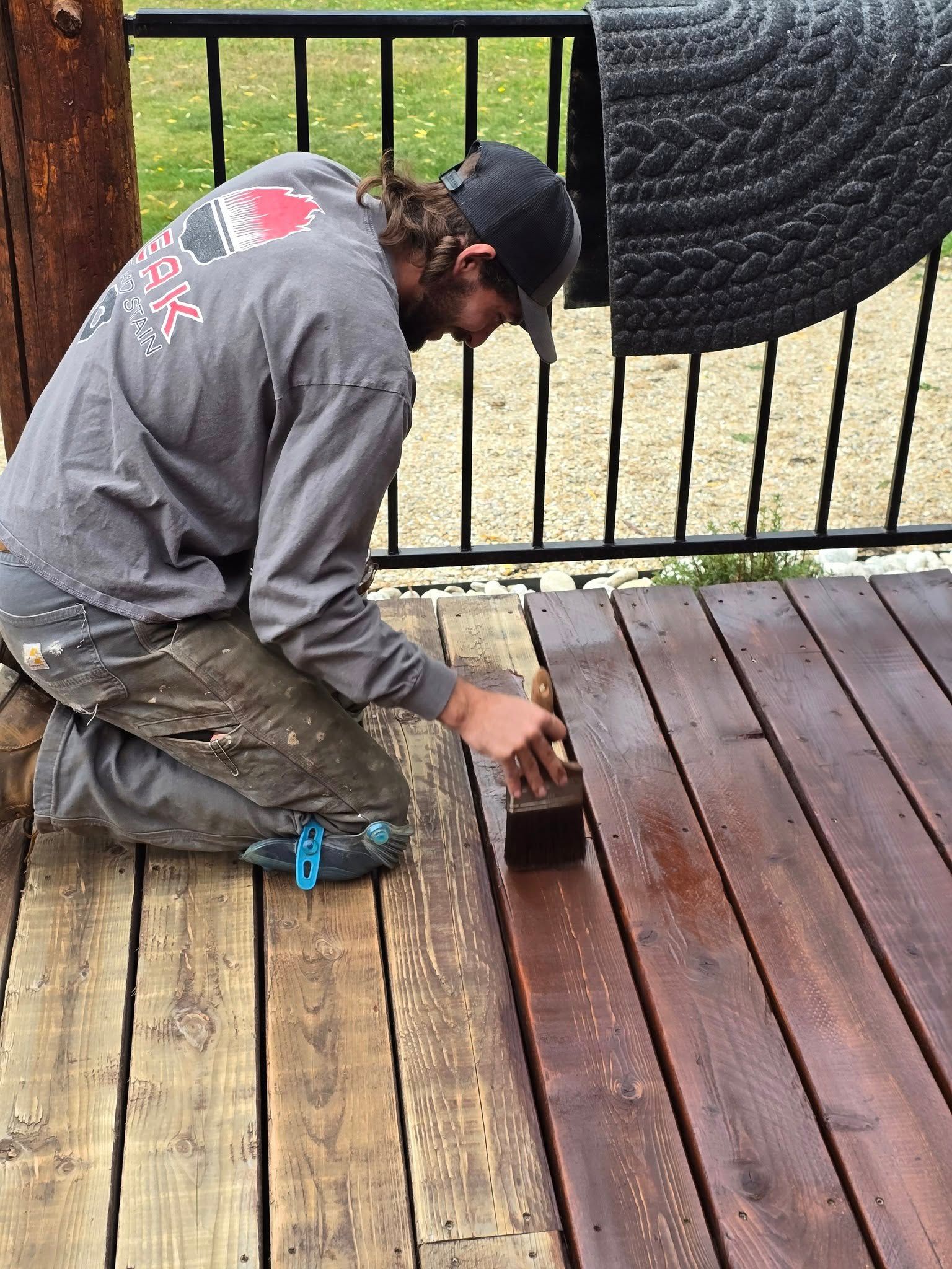 Person staining a wooden deck brown.