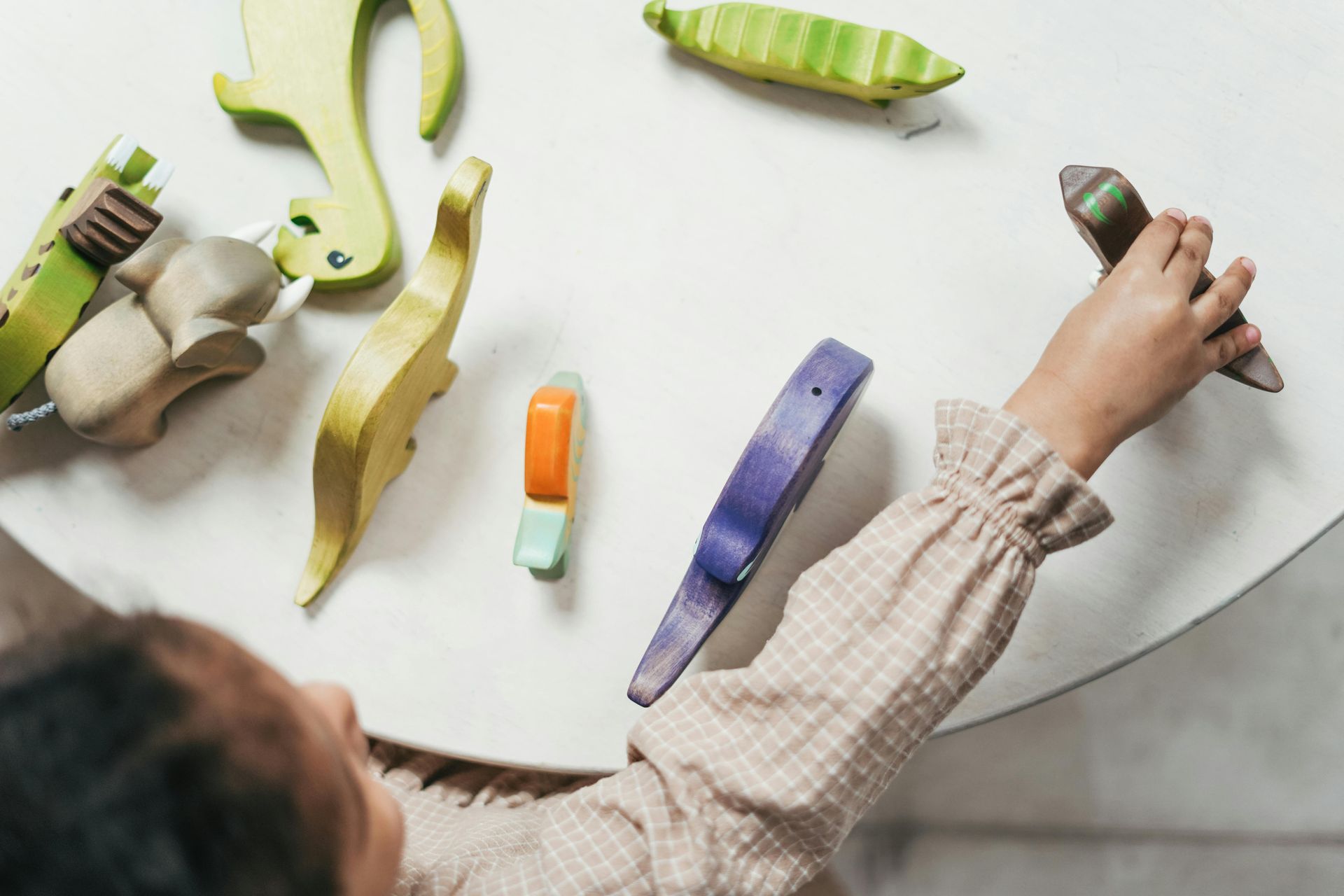Hand sorting colorful striped wooden blocks on a white table