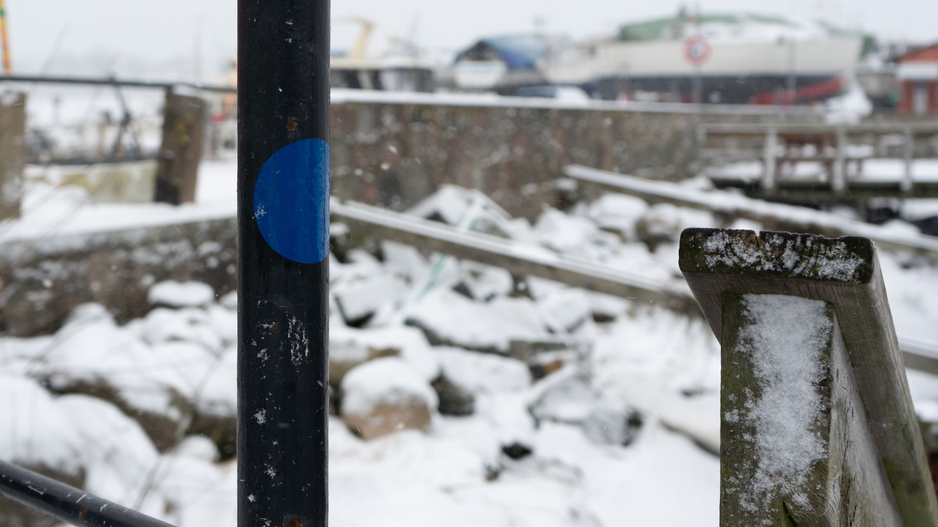 en sort pæl med en blå cirkel på er omgivet af sne.