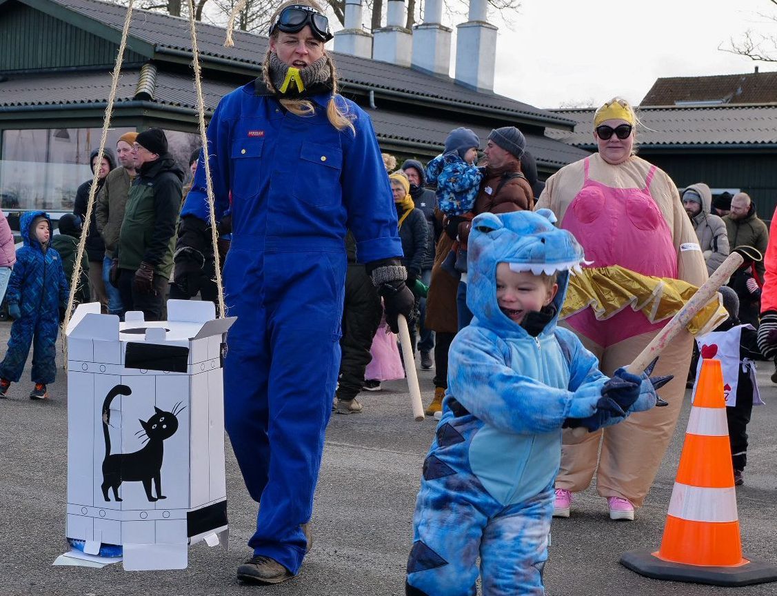 Lille dreng slår katten af tønden, med kvinder i baggrunden