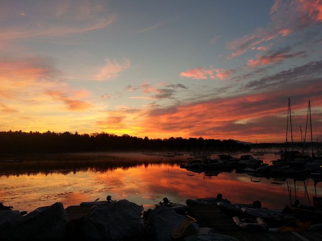 A sunset over a body of water with boats docked