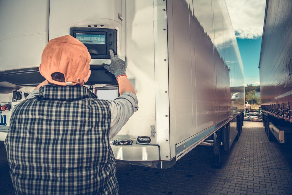 A Man Is Working on A Refrigerated Truck in A Parking Lot — Emu Park Automotive and Tyre Service in Emu Park, QLD
