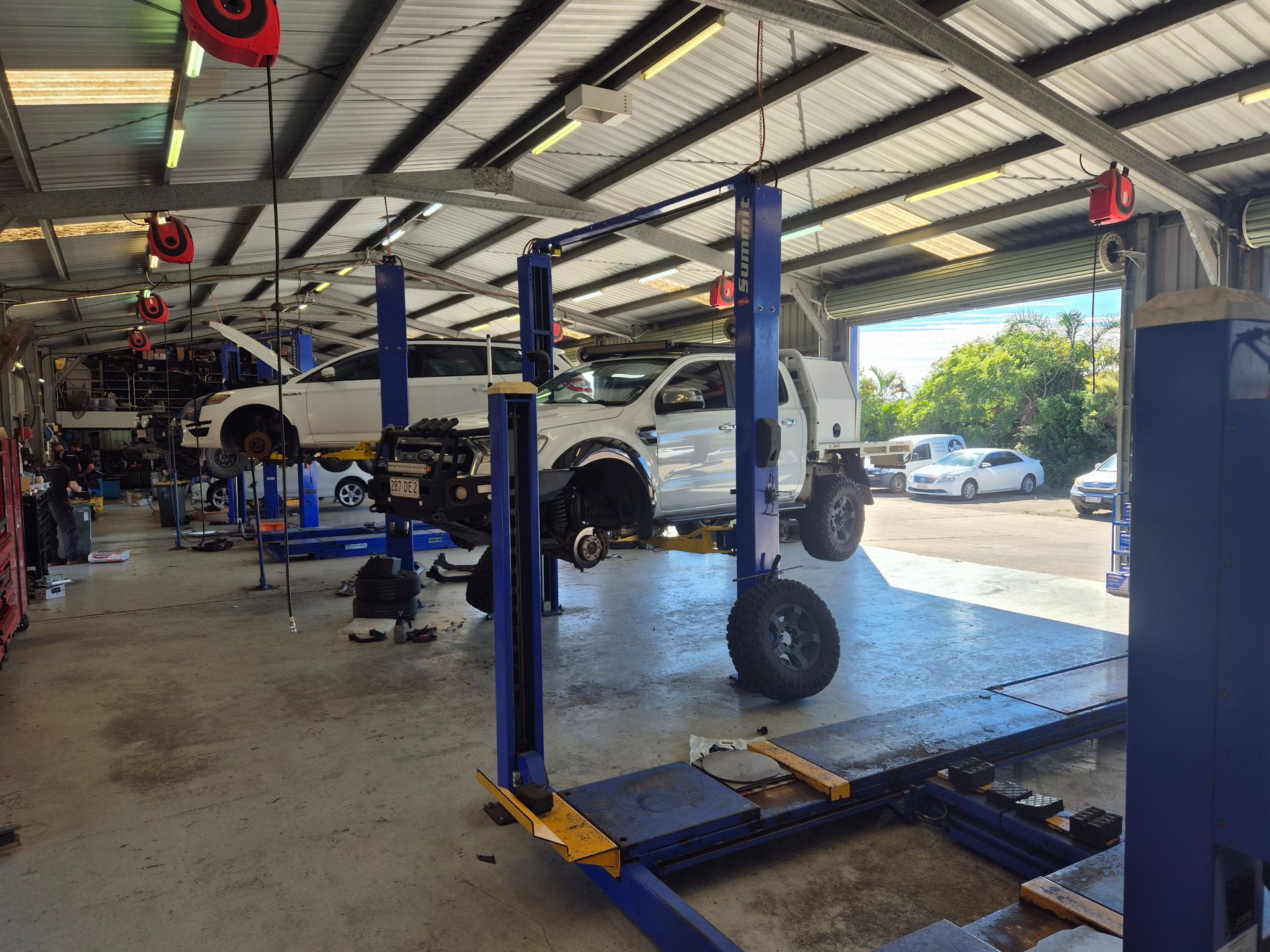 Auto repair shop with cars on lifts and tools in a bright service bay — Emu Park Automotive and Tyre Service in Emu Park, QLD
