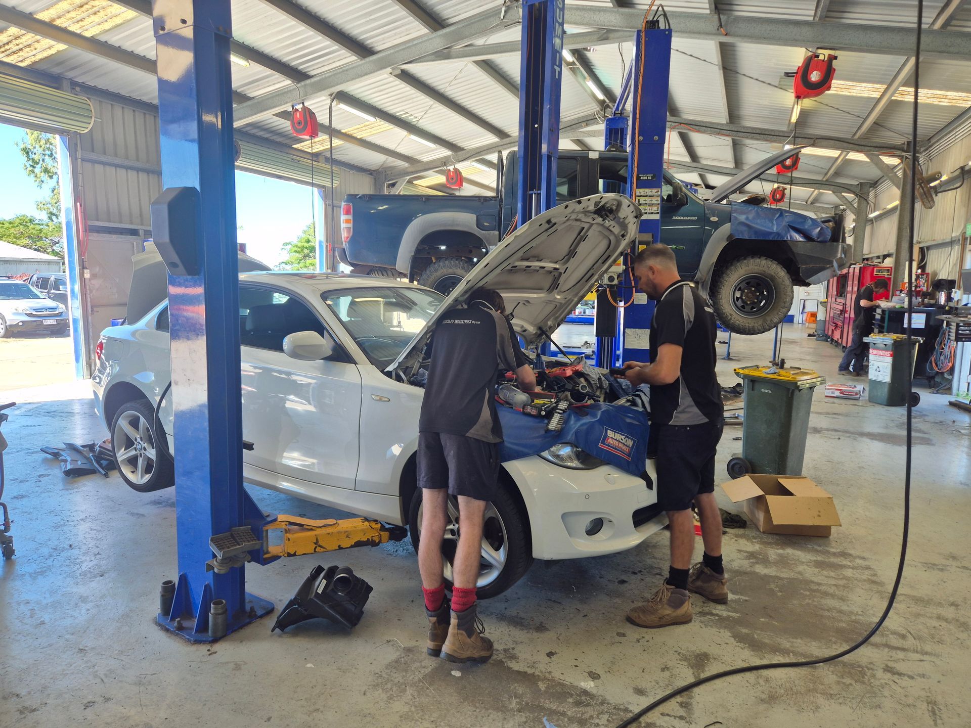 Mechanics Servicing a White Car in an Auto Repair Garage With Lifted — Emu Park Automotive and Tyre Service in Emu Park, QLD