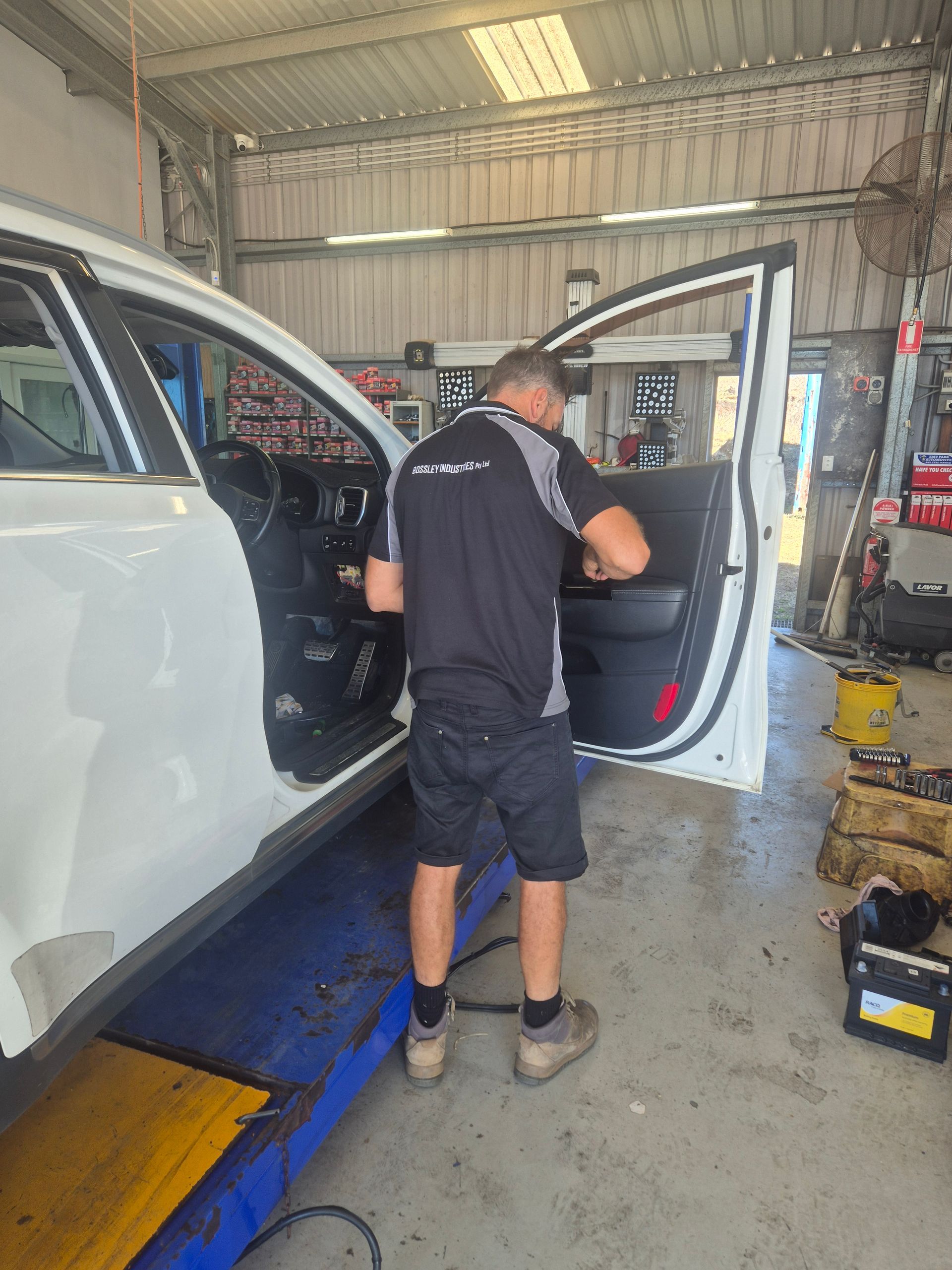 Mechanic Working on a White SUV in an Auto Repair Shop, Door Open — Emu Park Automotive and Tyre Service in Emu Park, QLD