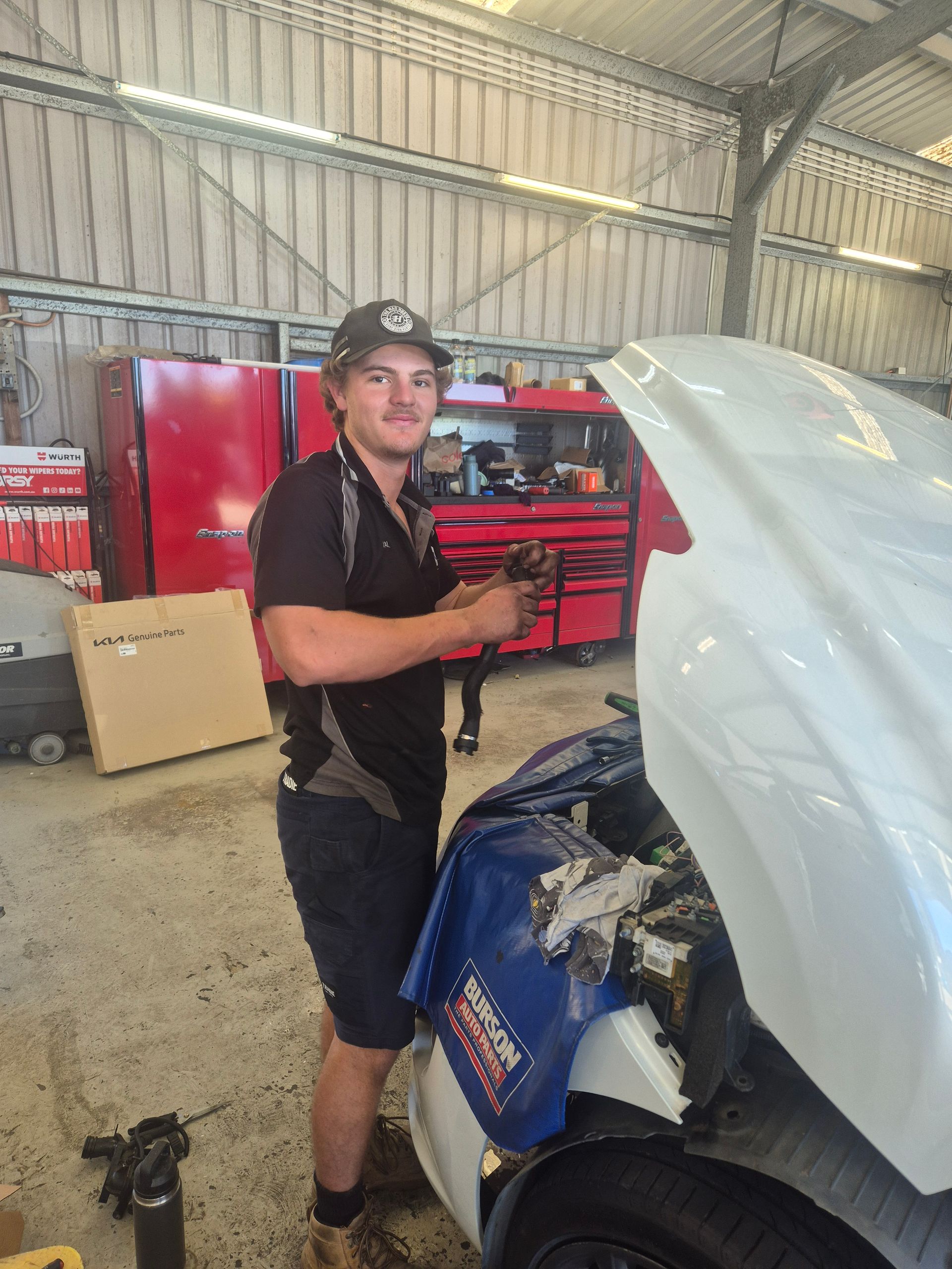 Mechanic in a Workshop Beside a Blue Car With Its Hood Open — Emu Park Automotive and Tyre Service in Emu Park, QLD