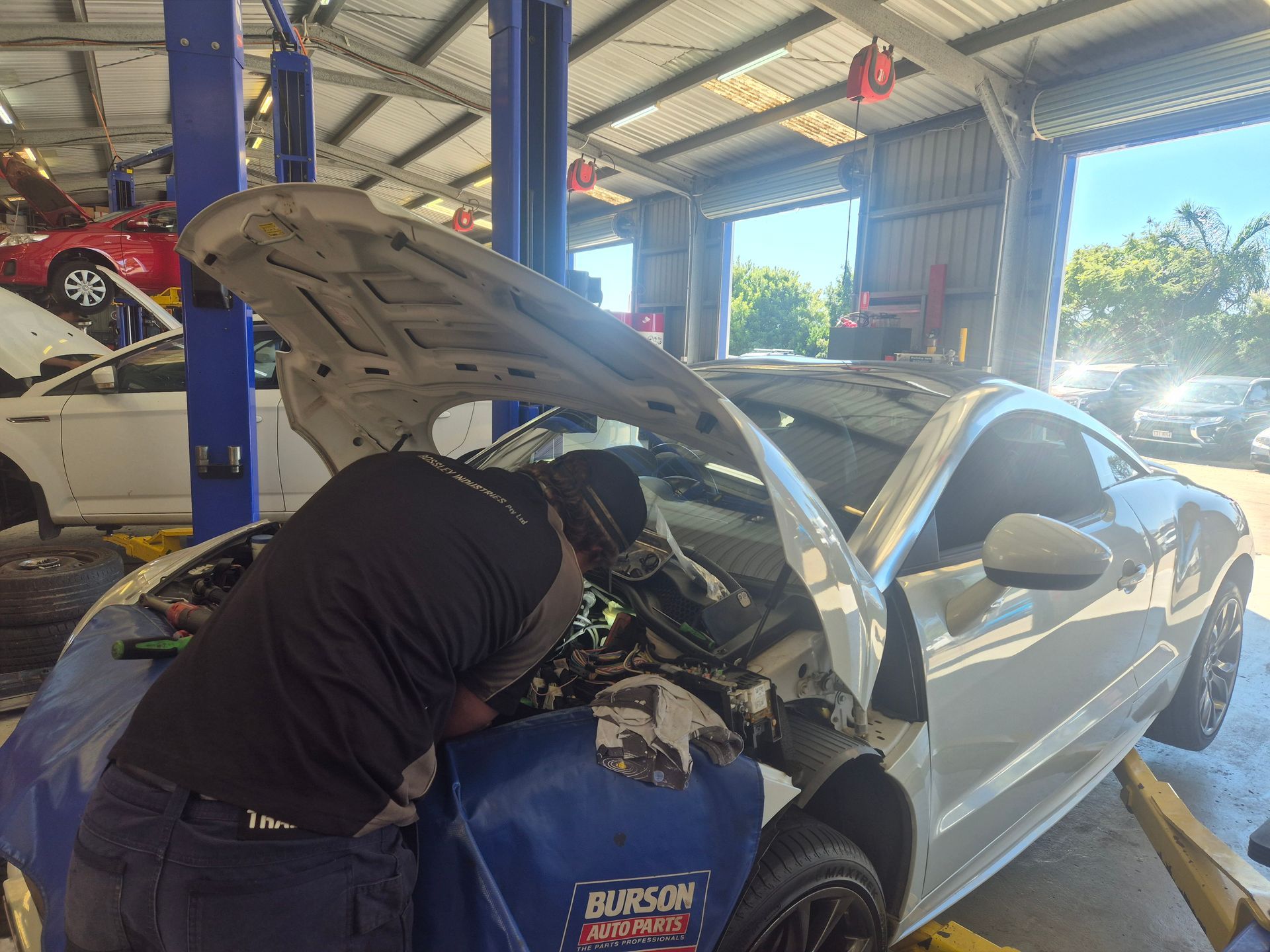 Mechanic Working Under Raised Hood of a Silver Car — Emu Park Automotive and Tyre Service in Emu Park, QLD