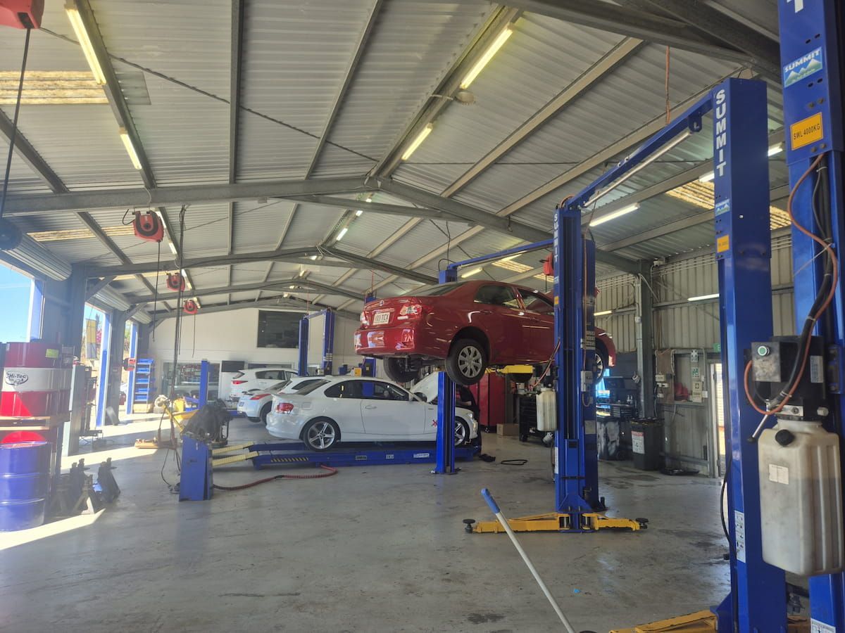 Auto Repair Shop With a Red Car Lifted on a Blue Hydraulic Hoist — Emu Park Automotive and Tyre Service in Emu Park, QLD