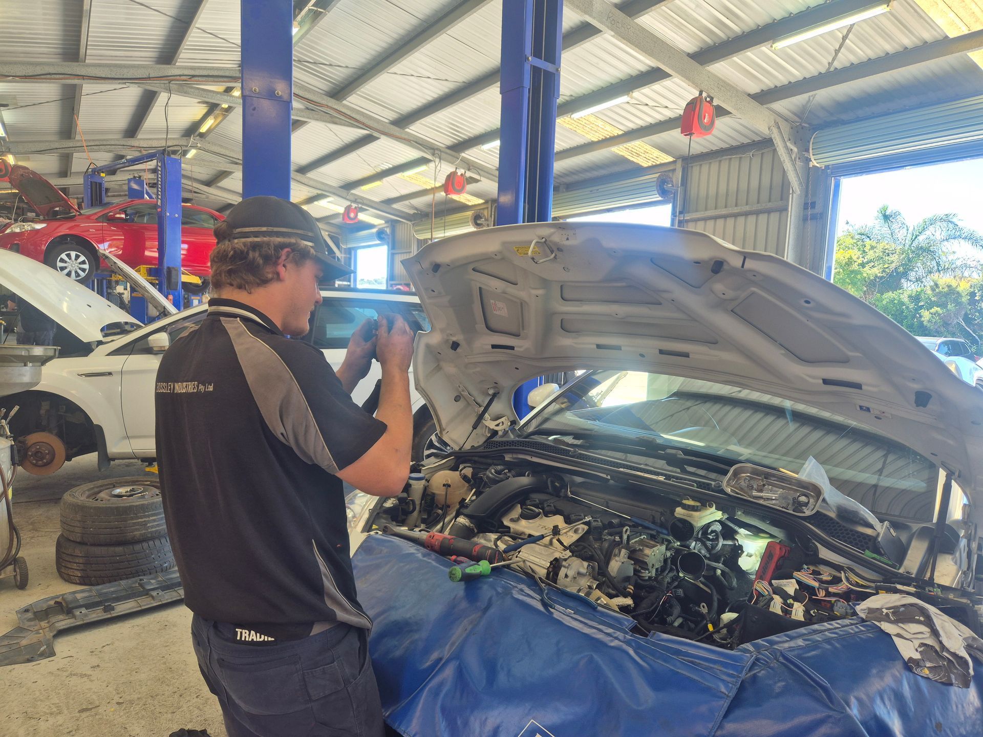 Mechanic inspecting an open car engine in a garage workshop — Emu Park Automotive and Tyre Service in Emu Park, QLD