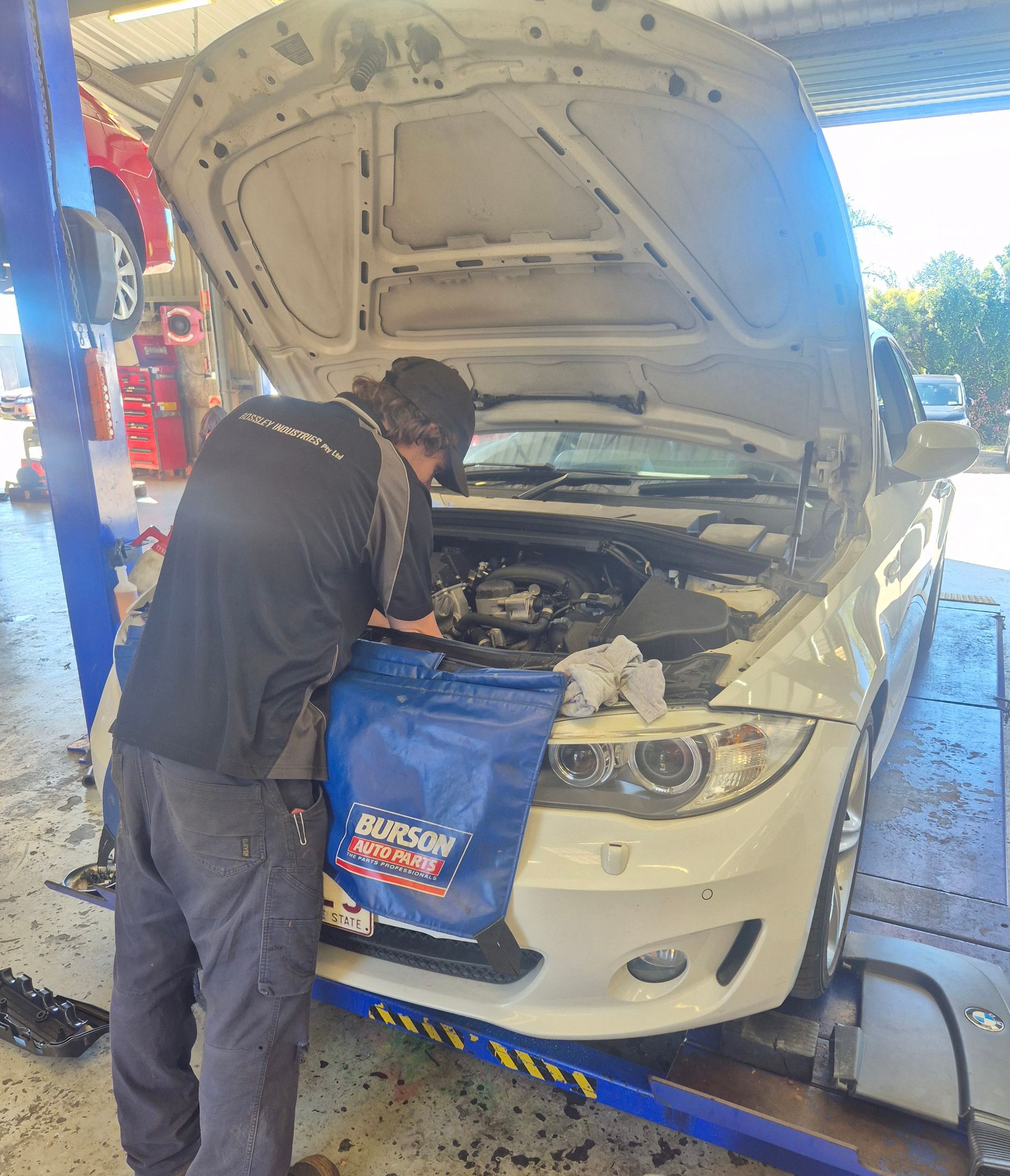 Mechanic Working Under the Hood of a White Car in a Repair Shop — Emu Park Automotive and Tyre Service in Emu Park, QLD