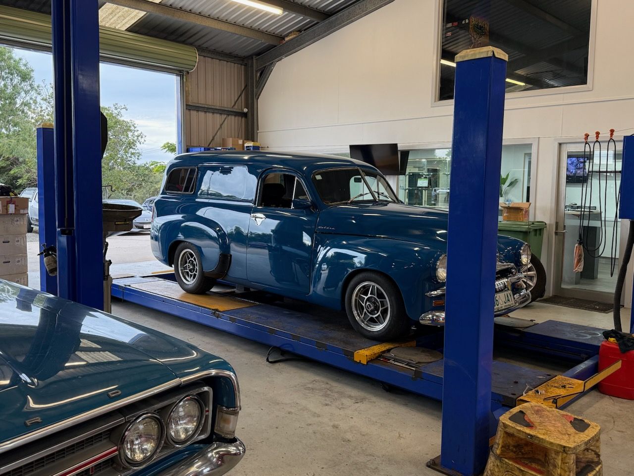 Blue classic station wagon on a car lift inside an auto repair shop — Emu Park Automotive and Tyre Service in Keppel Sands, QLD