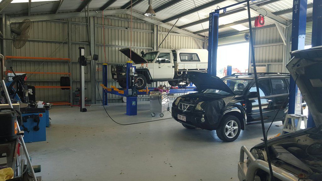Auto Repair Shop With a Black Car on a Lift and a White Van — Emu Park Automotive and Tyre Service in Coorooman, QLD