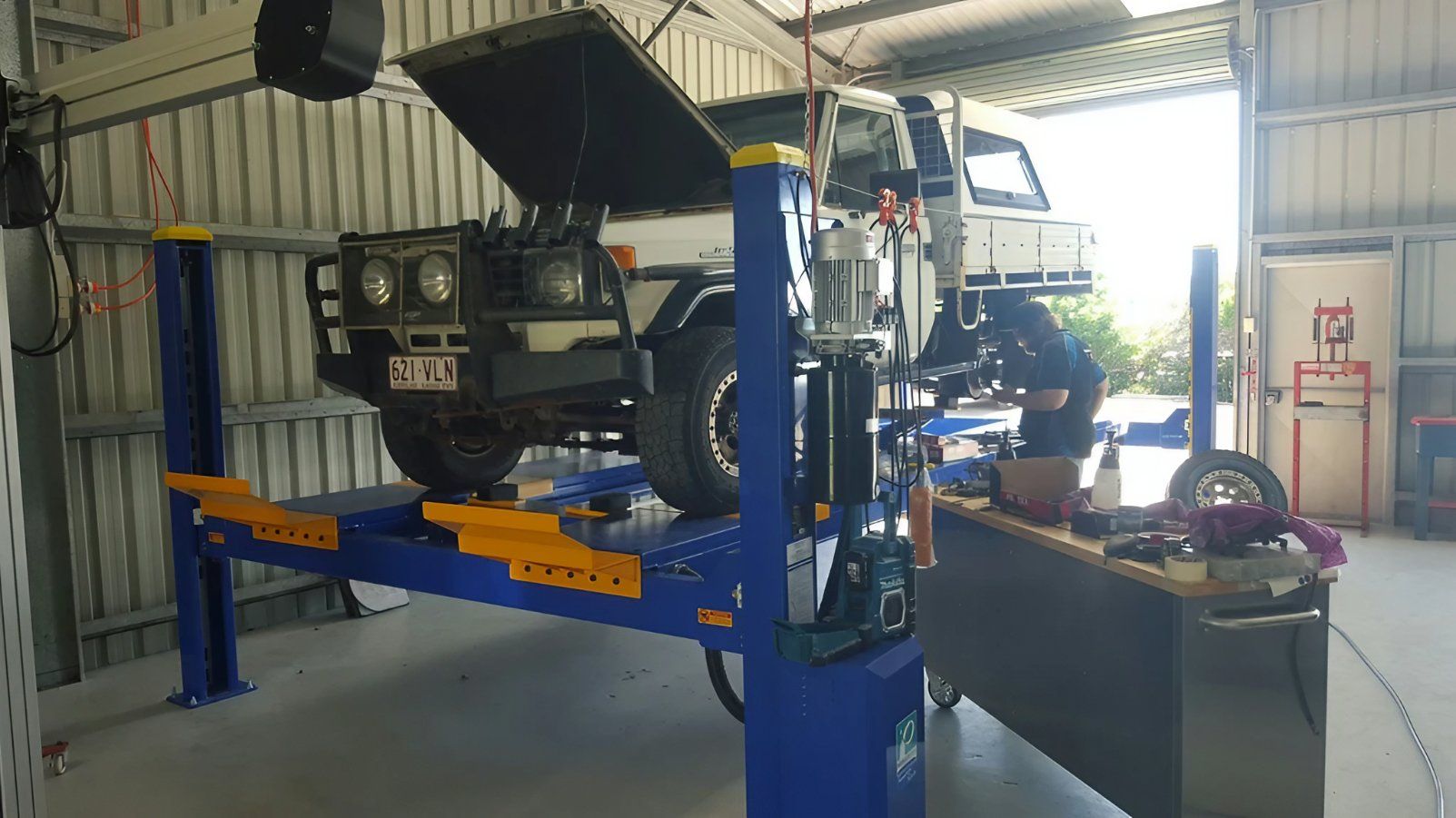 Blue Car Lift Holding a Vehicle Inside an Auto Repair Shop — Emu Park Automotive and Tyre Service in Tanby, QLD