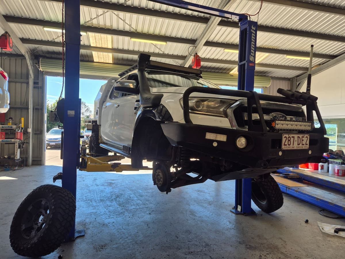 Off-road vehicle under repair in a garage, with front wheels removed and lifted on a hoist — Emu Park Automotive and Tyre Service in Keppel Sands, QLD