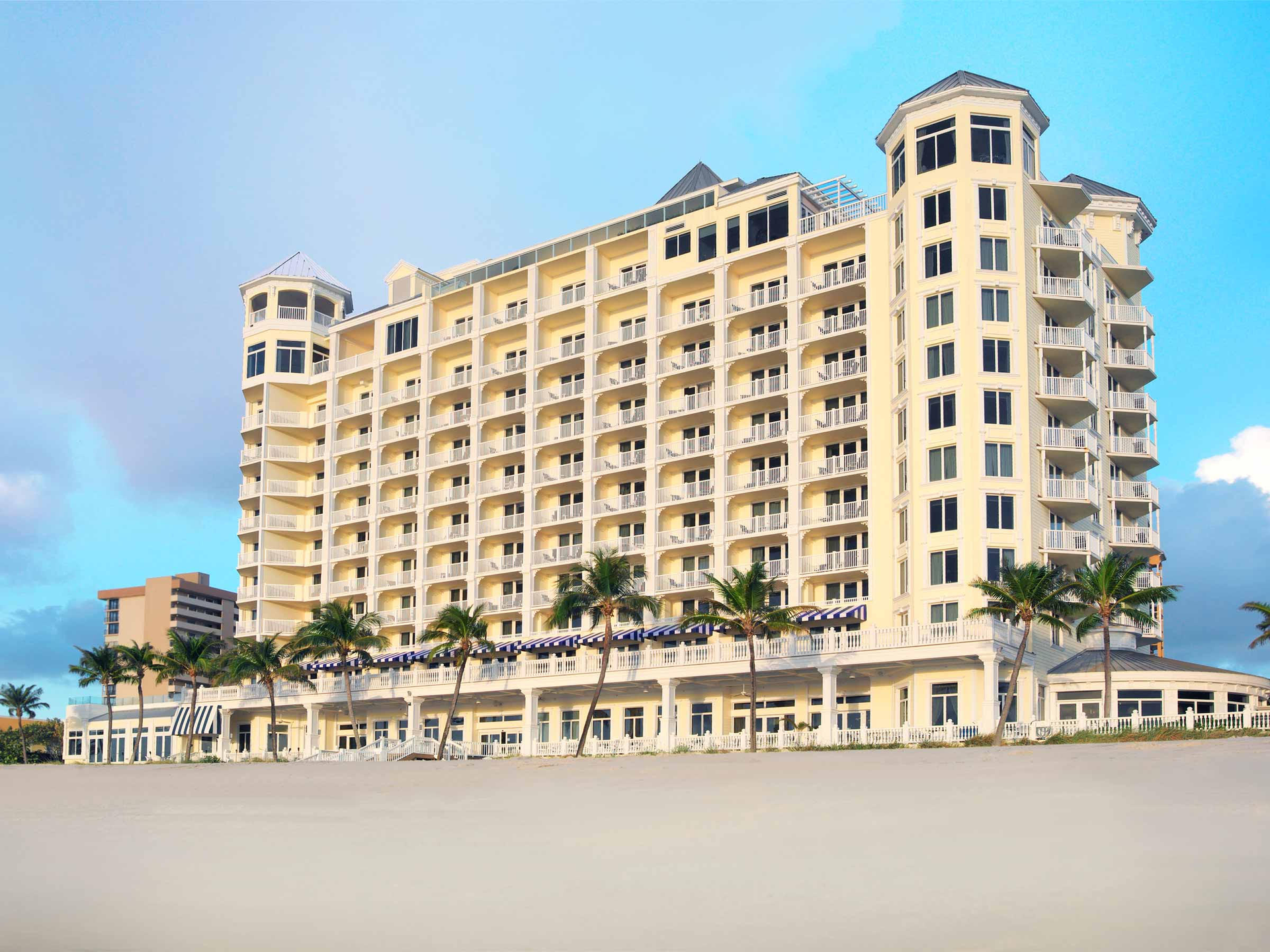 A large hotel is sitting on top of a sandy beach.